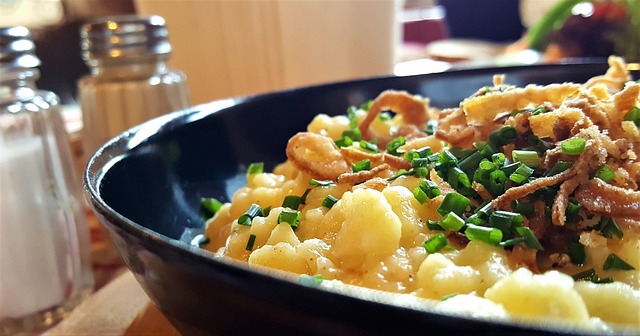 A large plate of German-pasta with cheese topped with fried onions and chives. This is Kaesespaetzle