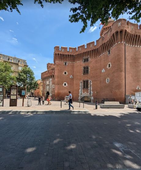 A view of the iconic Le Castillet in Perpignan with its turrets and red brick facade.