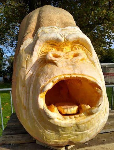 A carved pumkin in the shape of an ape with its mouth wide open.